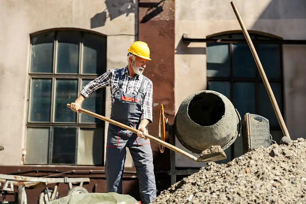 a construction worker shoveling wet concrete